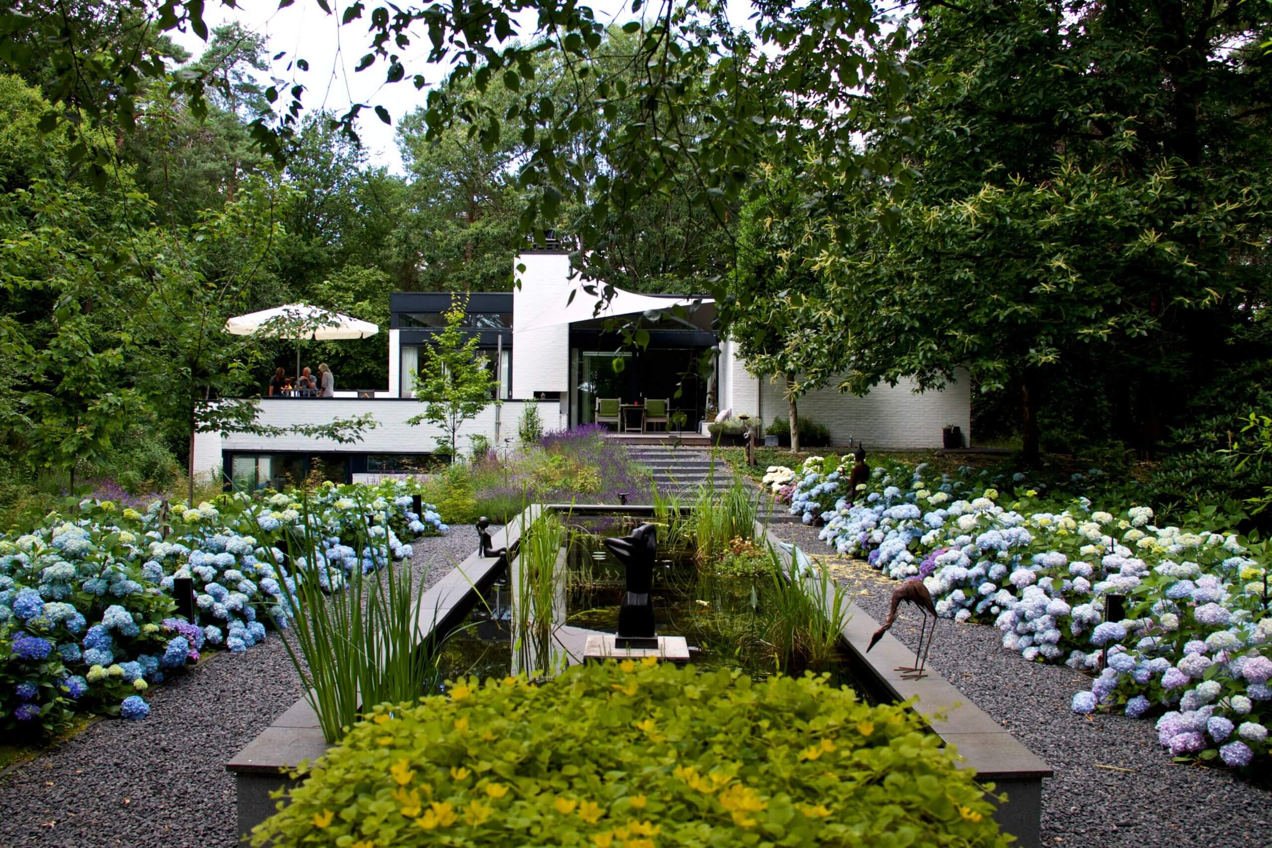 Bostuin met veel planten bij een moderne villa